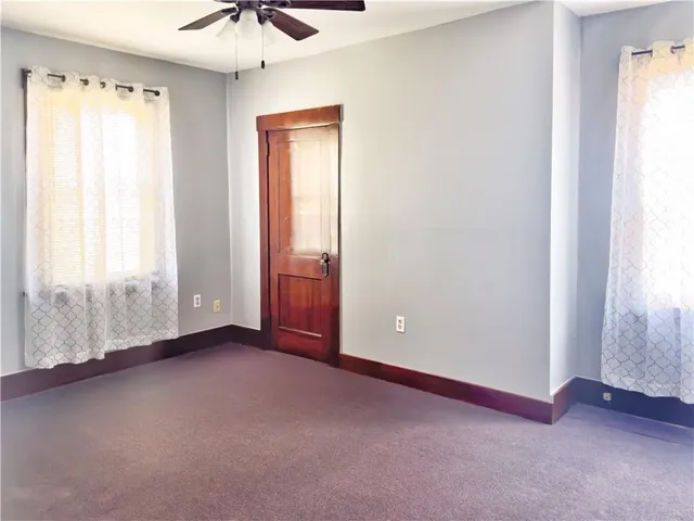 an empty room with windows and a chandelier fan