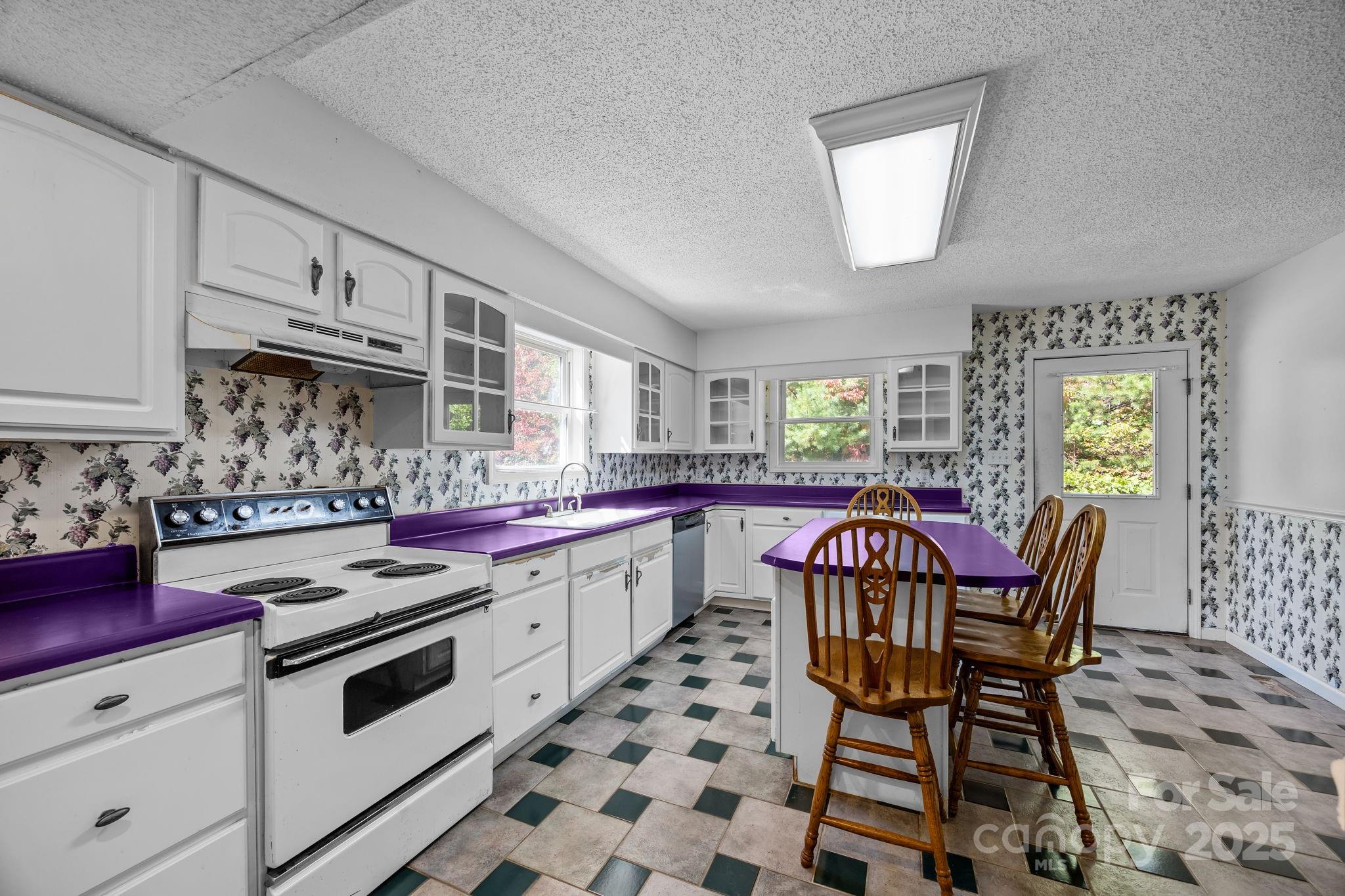 473 Eli Capps Road Zirconia, NC 28790 - Photo 18 of 37 a kitchen with stainless steel appliances a white stove top oven and a dining table with wooden floor