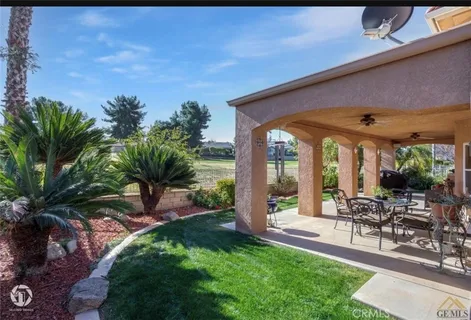 a view of a patio with table and chairs potted plants and palm tree