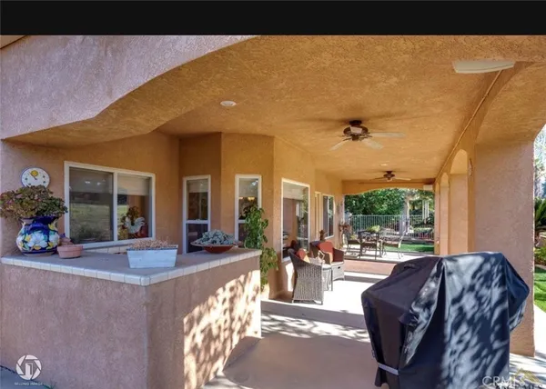 a view of a patio with table and chairs potted plants and floor to ceiling window