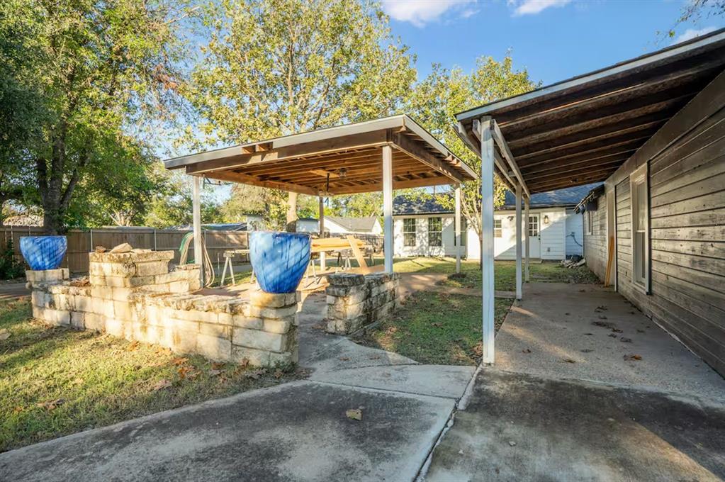 3210 Edna Avenue Waco, TX 76708 - Photo 17 of 18 a view of a patio with table and chairs under an umbrella with a large tree