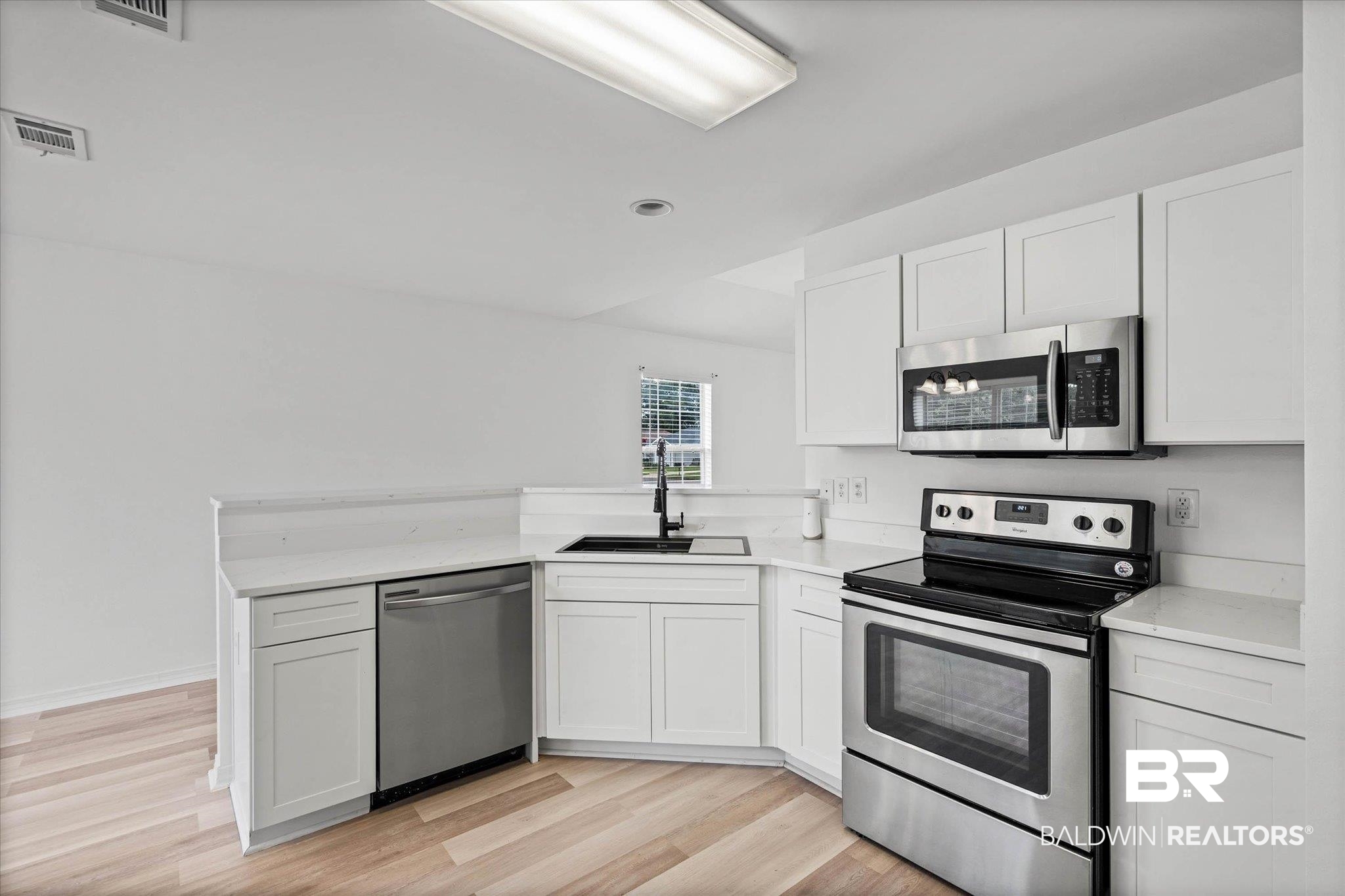 8980 Spring Grove North Mobile, AL 36695 - Photo 6 of 24 Contemporary kitchen featuring white cabinetry, light wood-finish flooring, stainless steel appliances, a black sink, and light countertops