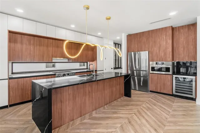 a kitchen with stainless steel appliances granite countertop a refrigerator a stove and a sink