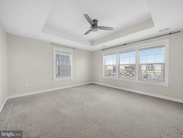 an empty room with windows and ceiling fan