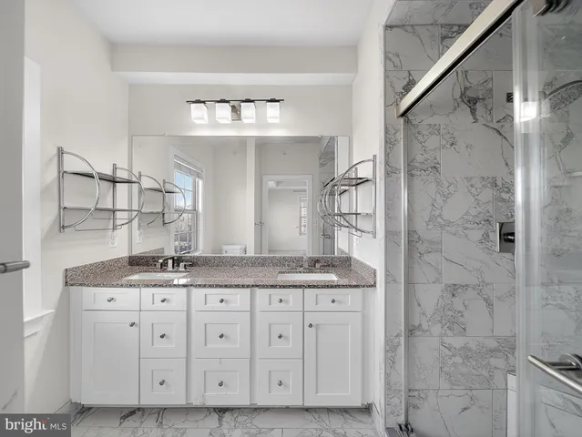 a bathroom with a granite countertop sink a mirror and a shower