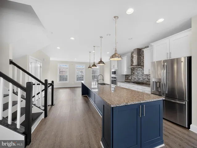 a kitchen with stainless steel appliances granite countertop a refrigerator a oven and a wooden floors