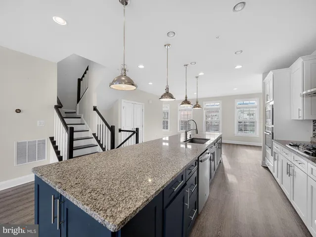 a kitchen with kitchen island a counter top space a sink a stove and wooden floor