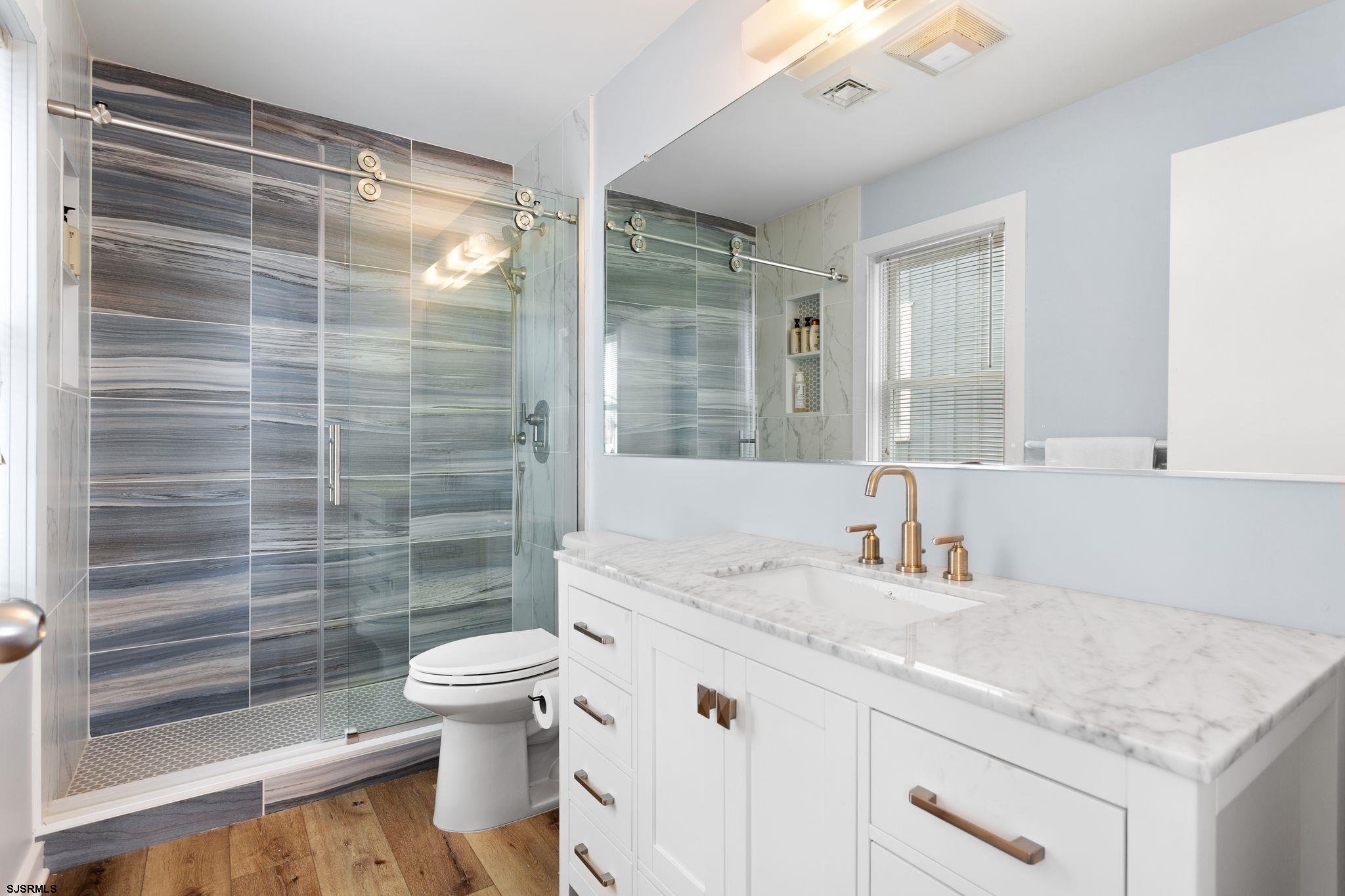 701 Lighthouse Road Cape May Point, NJ 08212 - Photo 7 of 32 a bathroom with a granite countertop sink a toilet a mirror and shower