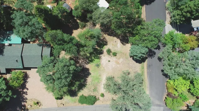 an aerial view of a house with a yard and trees all around
