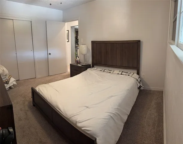 a bed sitting in a spacious bedroom next to a cabinet