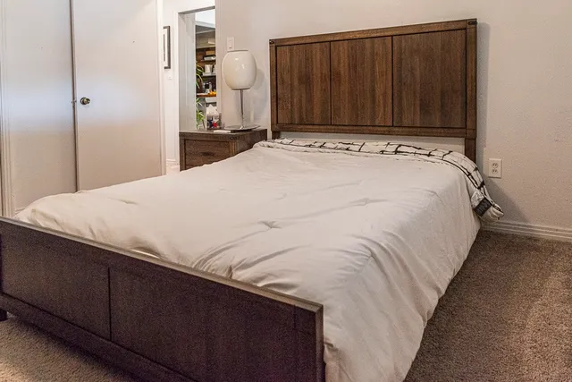 a bed sitting in a bedroom and wooden closet