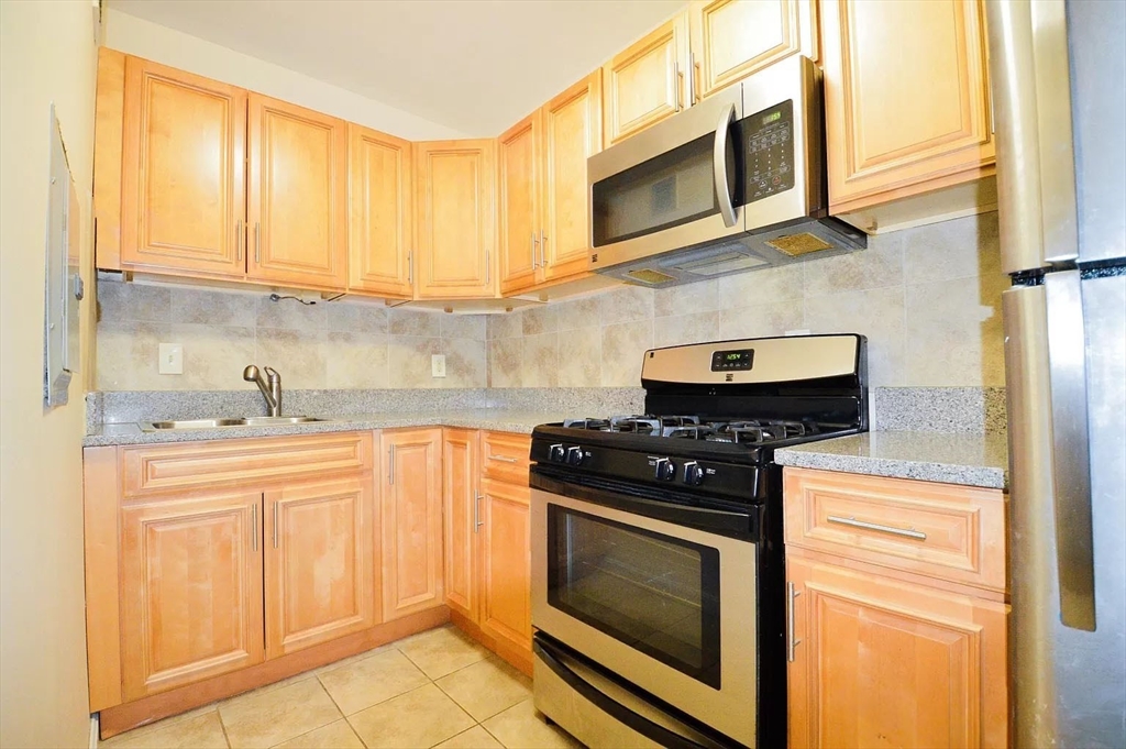 a kitchen with stainless steel appliances granite countertop white cabinets and black stove top oven