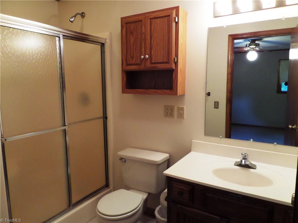 3308 Doub Road East Bend, NC 27018 - Photo 20 of 27 Master bathroom has a shower with a seat and a wall mounted cabinet. Vanity top and shower door will be new soon!