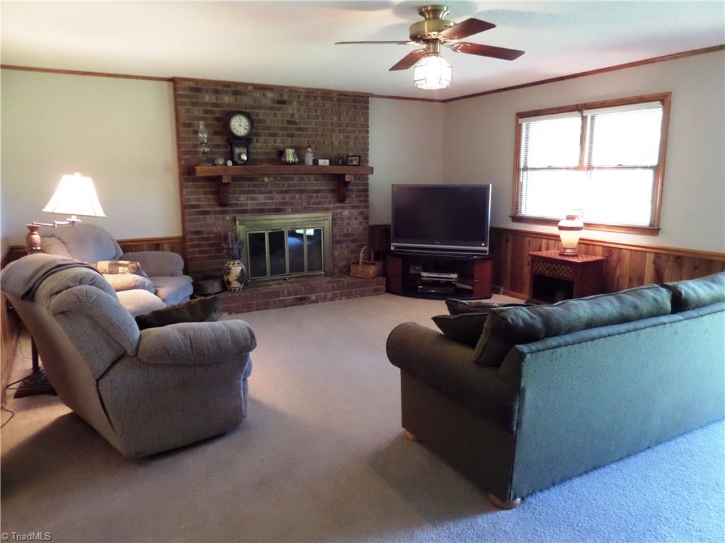 3308 Doub Road East Bend, NC 27018 - Photo 7 of 27 Spacious living room with crown molding, wainscoting, ceiling fan and a masonry fireplace with gas logs. There is also a coat closet by the front door.
