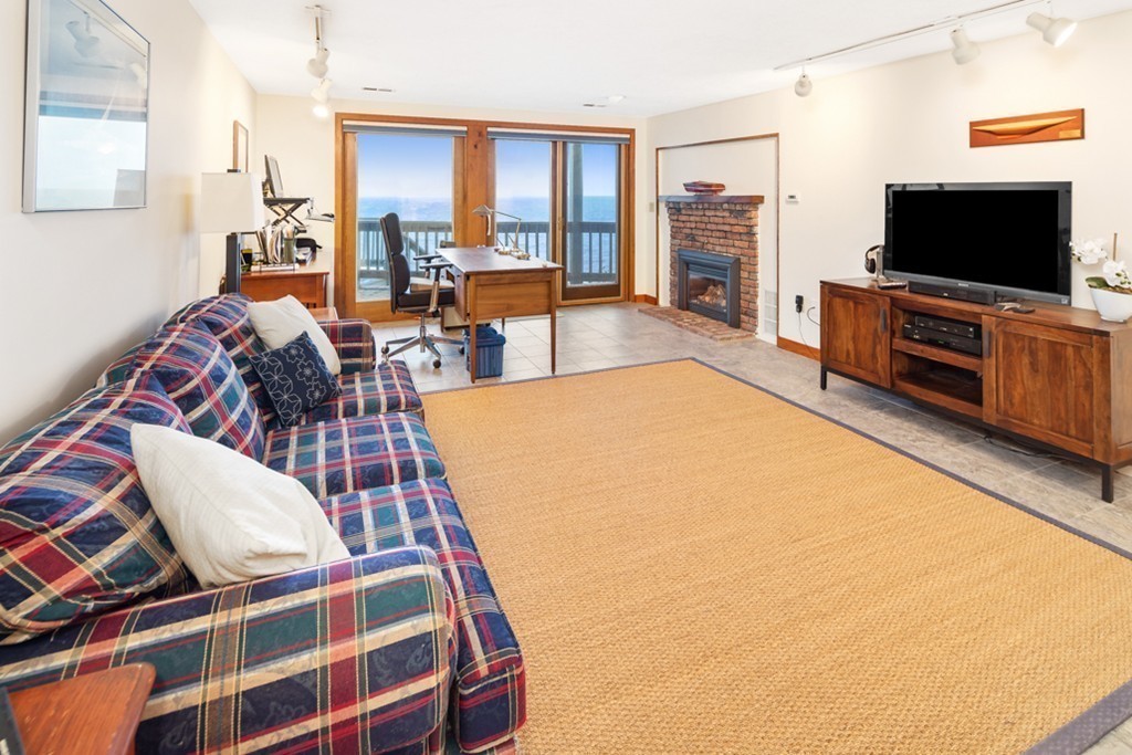 13 Oceanside Drive, Unit 13 Hull, MA 02045 - Photo 14 of 27 a living room with furniture a flat screen tv and a floor to ceiling window