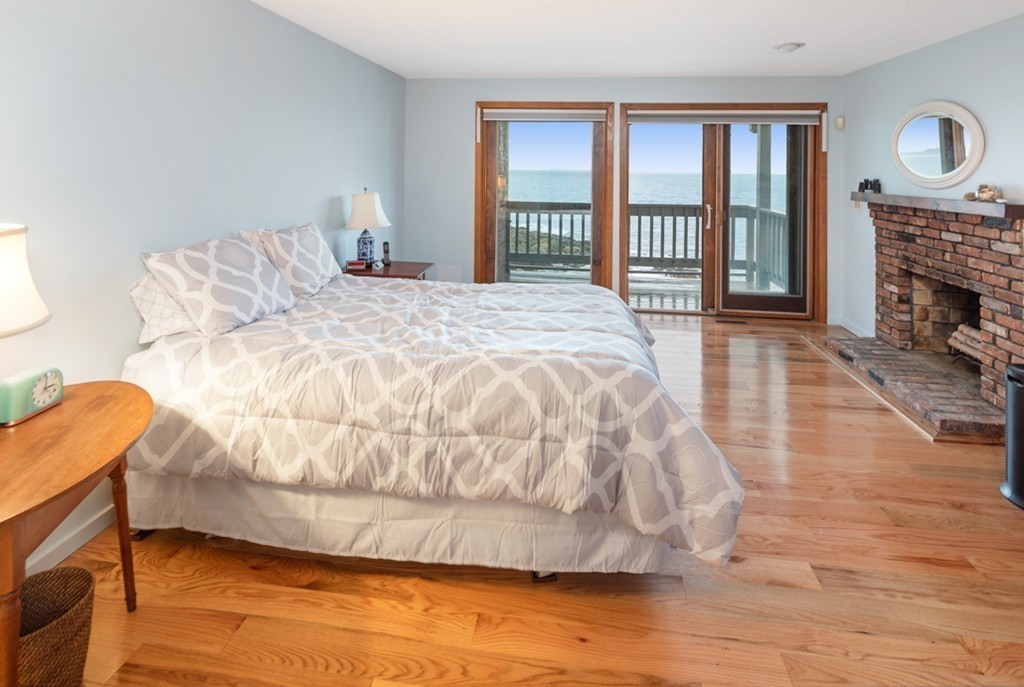 13 Oceanside Drive, Unit 13 Hull, MA 02045 - Photo 10 of 27 a large bed sitting in a bedroom next to a fireplace and window