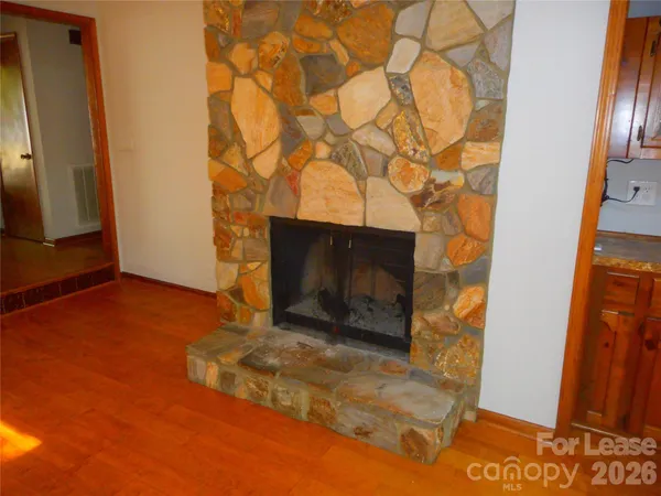 a view of an empty room with wooden floor and a fireplace