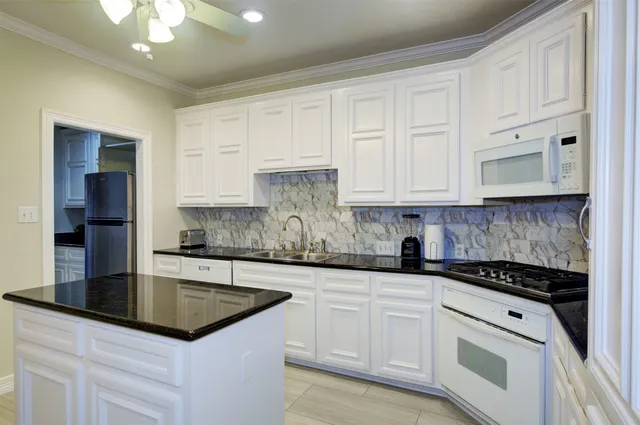 a kitchen with kitchen island granite countertop a sink a stove and cabinets