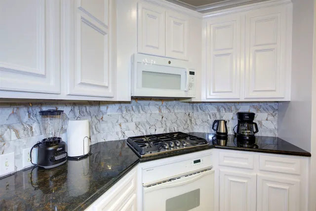 a kitchen with white cabinets and appliances