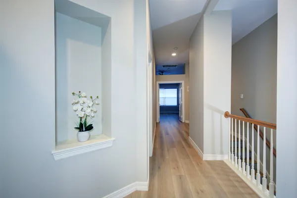 a view of a hallway with wooden floor and a bathroom