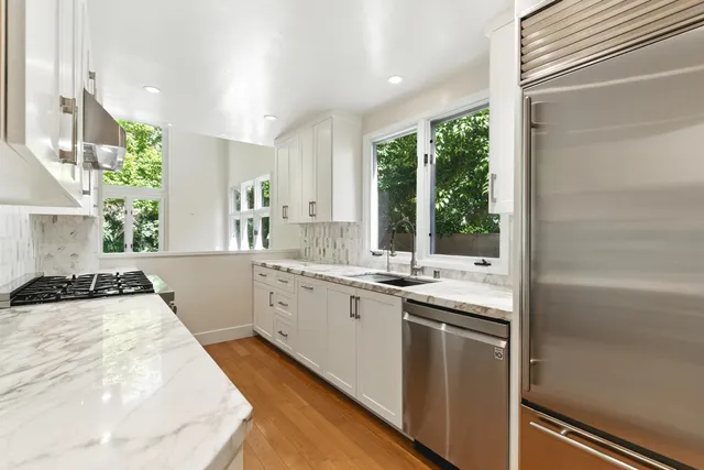 a kitchen with granite countertop a sink and white cabinets