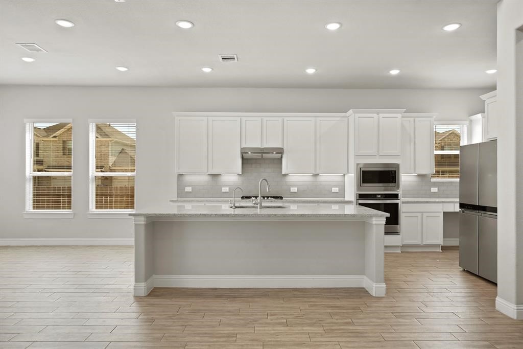 31302 Quartet Court Fulshear, TX 77441 - Photo 11 of 32 a kitchen with kitchen island a stove a sink and a refrigerator