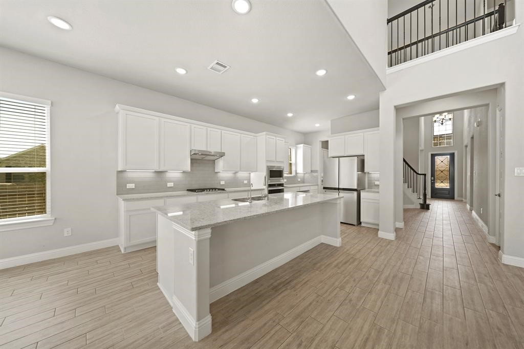 31302 Quartet Court Fulshear, TX 77441 - Photo 12 of 32 a kitchen with stainless steel appliances granite countertop a white cabinets and wooden floors