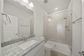 31302 Quartet Court Fulshear, TX 77441 - Photo 22 of 32 a bathroom with a granite countertop sink a toilet and shower