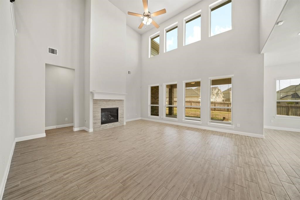 31302 Quartet Court Fulshear, TX 77441 - Photo 7 of 32 an empty room with wooden floor fireplace and windows