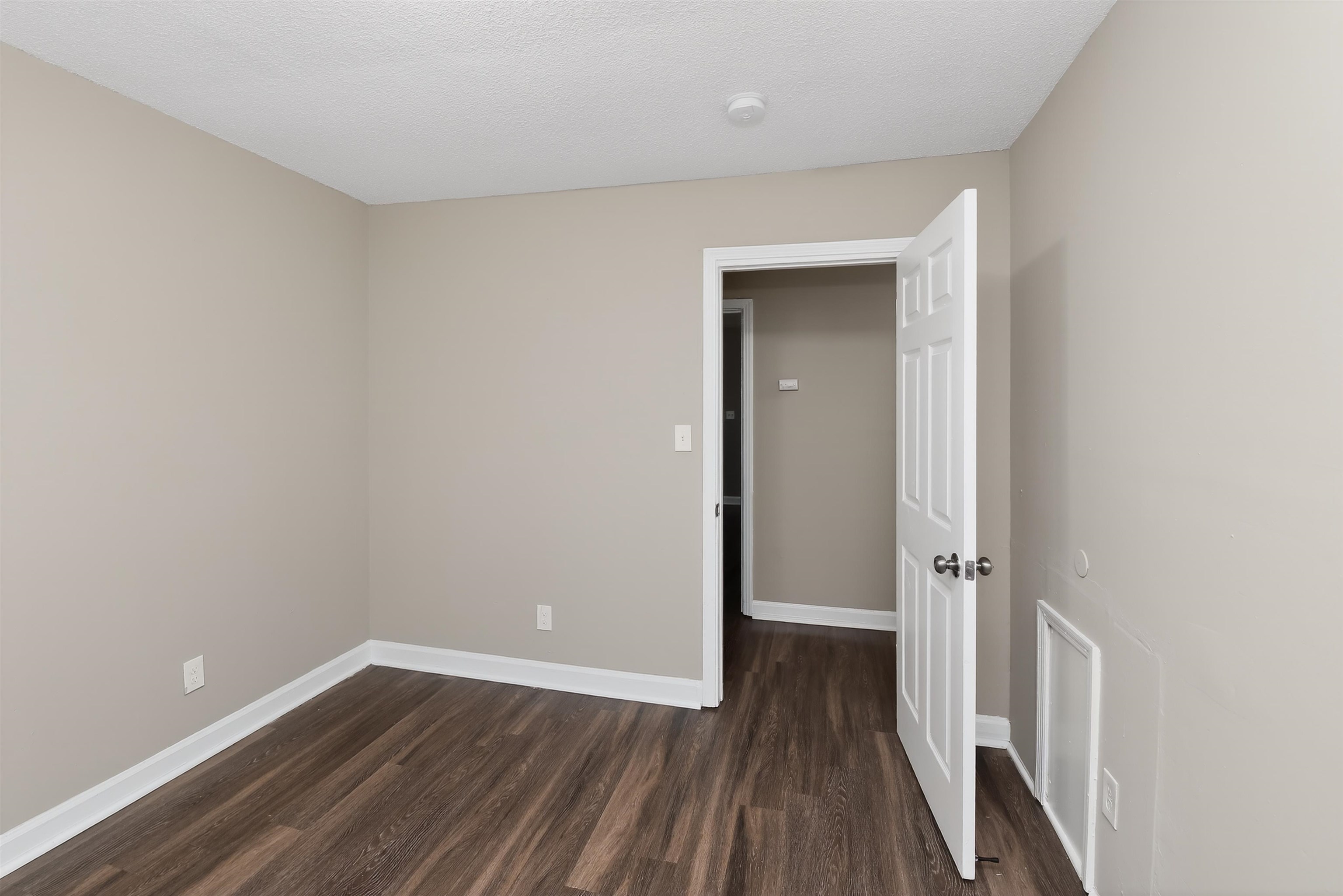 318 East Raines Road Memphis, TN 38109 - Photo 18 of 28 Neutral-toned interior room featuring wood-finish flooring, white baseboards, and a paneled interior door with chrome hardware