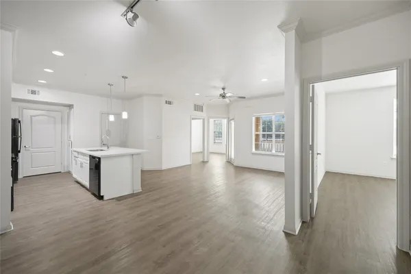 a view of an empty room and kitchen with a sink