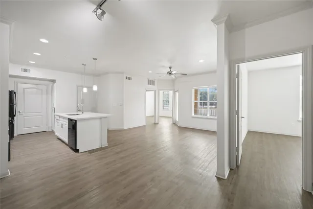 a view of an empty room and kitchen with a sink