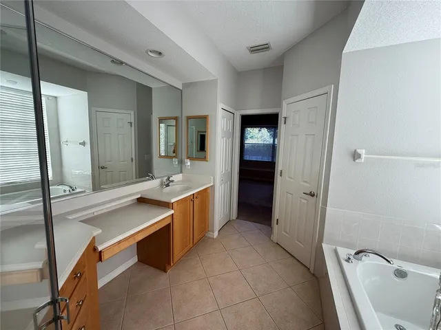 a spacious bathroom with a tub sink and mirror