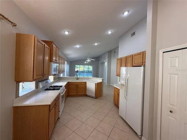 a kitchen with stainless steel appliances granite countertop a refrigerator a sink dishwasher a oven with white cabinets and countertops