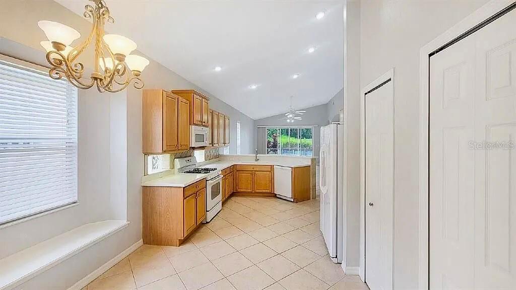 6055 Wingspan Way Bradenton, FL 34203 - Photo 9 of 32 a kitchen with stainless steel appliances granite countertop a refrigerator a sink dishwasher a oven with white cabinets and countertops