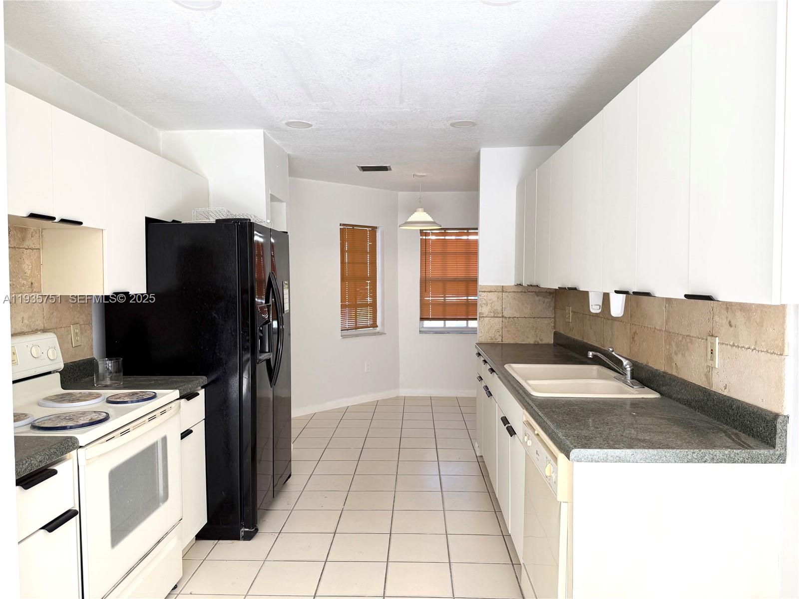 13922 Southwest 102nd Lane Miami, FL 33186 - Photo 7 of 20 a kitchen with a sink a counter top space and stainless steel appliances