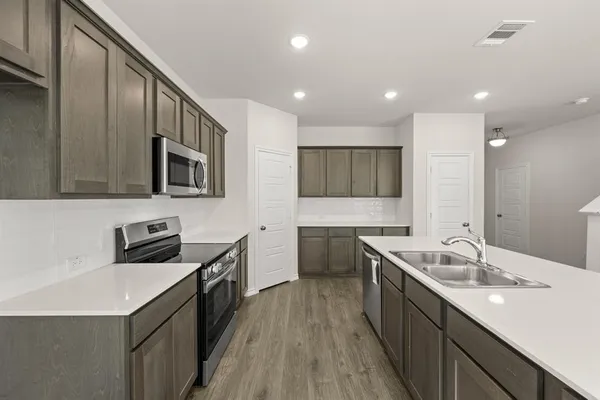 a kitchen with stainless steel appliances granite countertop a sink a stove top oven a refrigerator with island and chairs