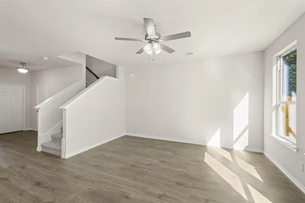 a view of an empty room with a window and wooden floor