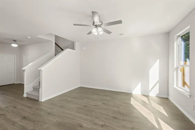 a view of an empty room with a window and wooden floor