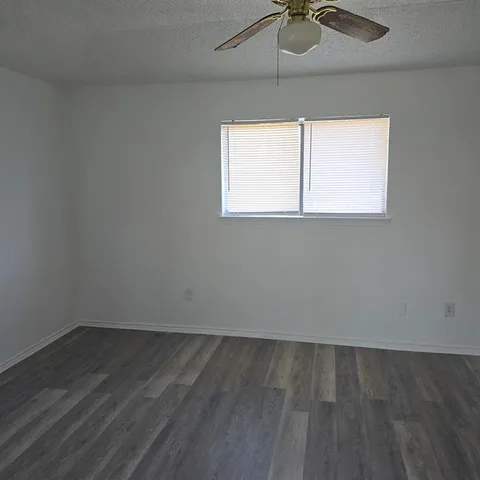 an empty room with a window and a ceiling fan