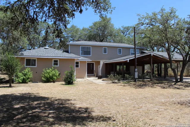 a front view of a house with a yard covered with trees