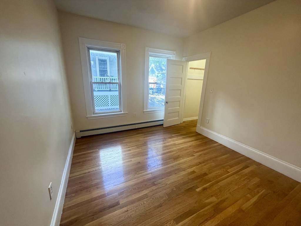 19 Banks Street, Unit 1 Somerville, MA 02144 - Photo 11 of 16 an empty room with wooden floor and windows