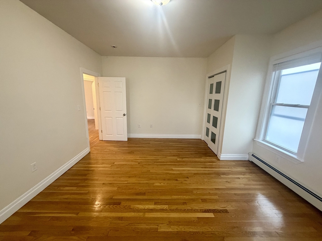 19 Banks Street, Unit 1 Somerville, MA 02144 - Photo 8 of 16 a view of an empty room with wooden floor and a window