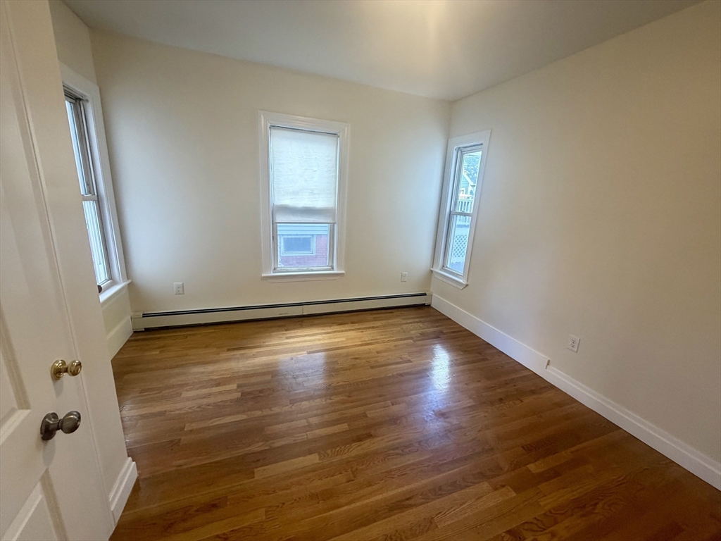 19 Banks Street, Unit 1 Somerville, MA 02144 - Photo 9 of 16 an empty room with wooden floor and windows