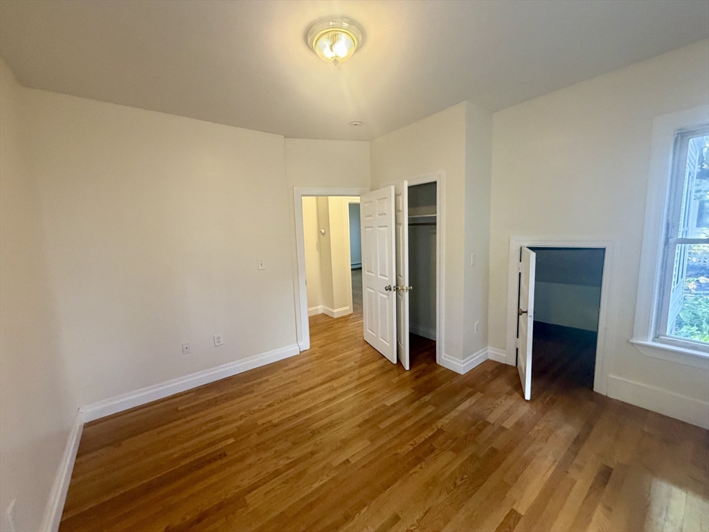 19 Banks Street, Unit 1 Somerville, MA 02144 - Photo 10 of 16 an empty room with wooden floor and windows