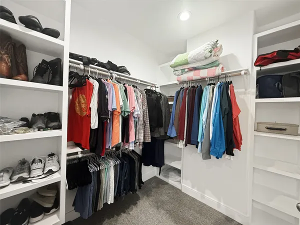 a view of walk in closet with clothes and shoes