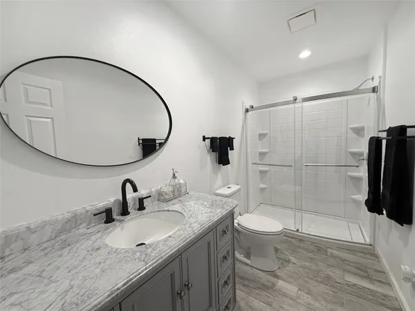 a bathroom with a granite countertop sink a toilet and a mirror