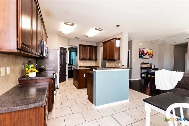 a kitchen with stainless steel appliances granite countertop a stove a refrigerator and a sink