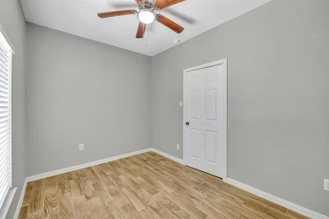 an empty room with a window and a chandelier fan