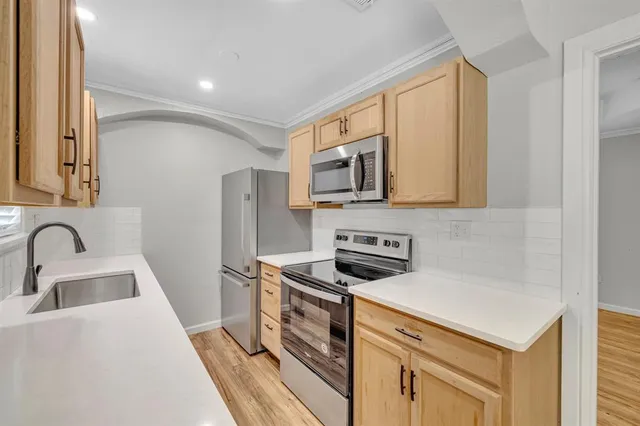 a kitchen with stainless steel appliances a sink a stove a microwave a refrigerator a counter space and cabinets